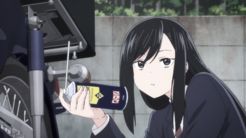 Reika applying solvent to a screw beneath the motorcycle
